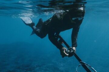 A spearfisher dives underwater in the clear blue waters of Hawaii.