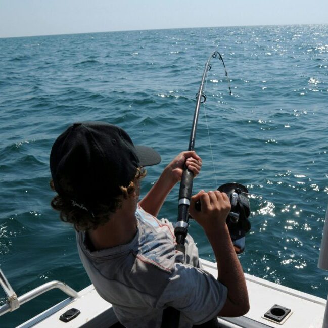 A young man actively fishing in the ocean near Broome, WA, enjoying a sunny day.